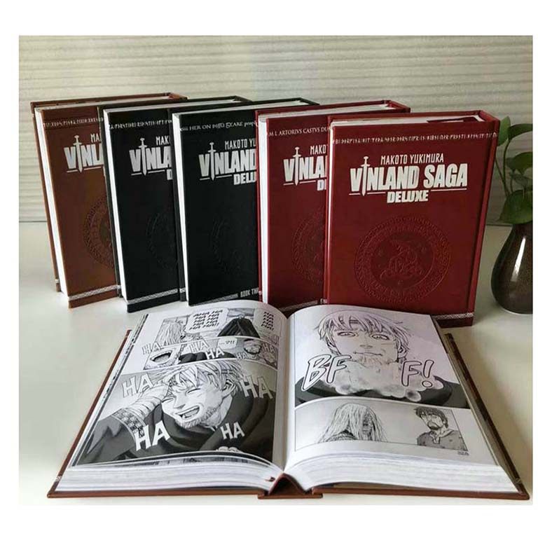 Vinland Saga Deluxe hardcovers displayed upright with one volume open to black-and-white interior manga pages